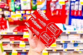 hand holding up two colgate toothpastes