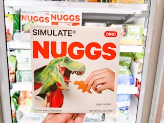 hand holding a box of Simulate Nuggs Dinos in front of a Target storage freezer