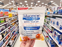 hand holding mucinex cough drops in aisle