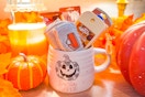 a halloween themed mug filled with boo basket items like socks and hand sanitizer 