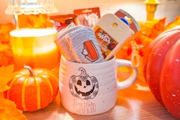 a halloween themed mug filled with boo basket items like socks and hand sanitizer 
