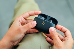 Person holding earbud container.