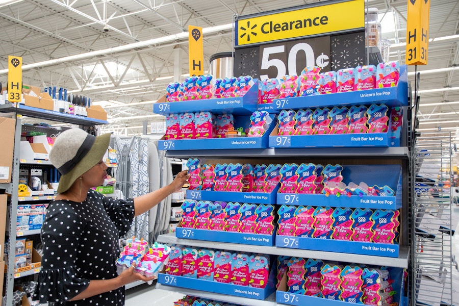 woman at a Walmart endcap picking up Cool Gear ice pop makers off the shelf that says Clearance 50 cents. 