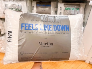 Feels like Down Pillow on in hand with shelf full of martha stewart products in background