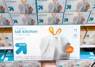 hand holding box of garbage bags in front of store shelf of boxes of garbage bags