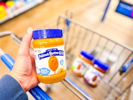 hand holding a peanut butter spread in front of other flavor spreads