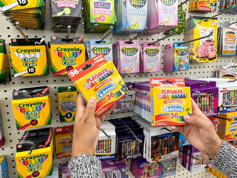 a person holding playschool crayons in store 