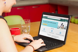 a person looking at the amazon website on a laptop while sitting in a kitchen 