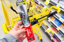 hand holding colgate charcoal toothbrush next to dollar general shopping cart