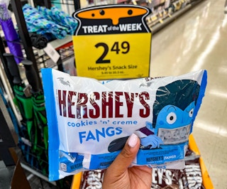hand holding bag of Hershey's cookies n creme fangs candy bag in front of sale sign