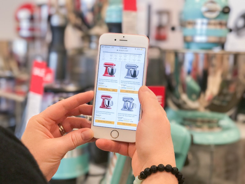 A woman holds a phone with Amazon kitchenaid mixers on it.