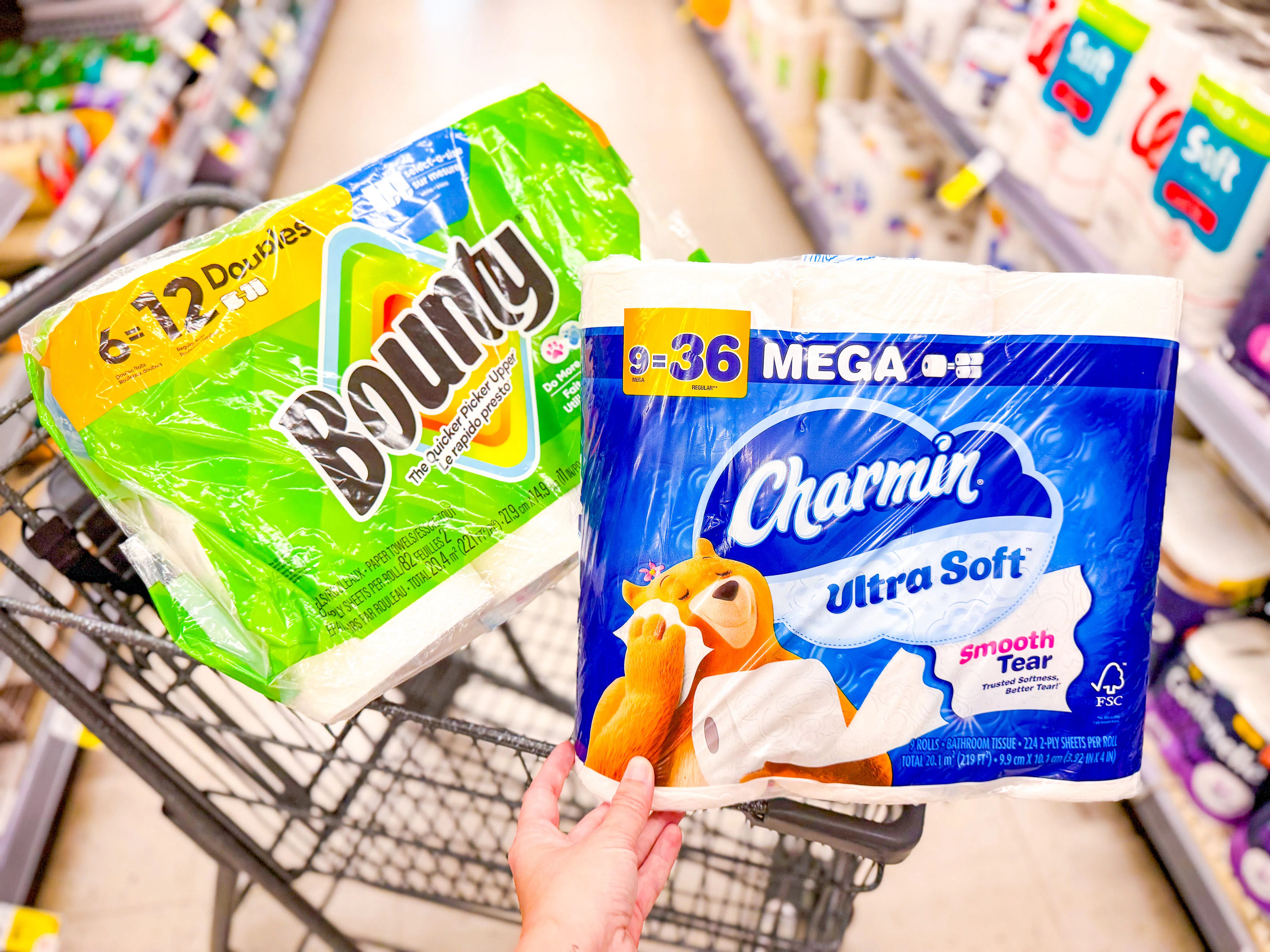 Bounty and Charmin paper products stacked on a shelf at Walgreens with a sale sign showing $18 price