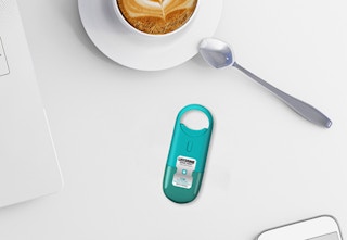 a blue breath spray on a table next to a cup of coffee