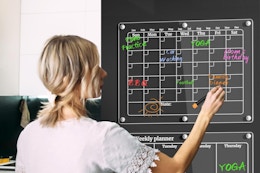 woman writing on calendar on fridge