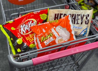 Bags of Halloween candy in the basket of a shopping cart.