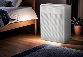 an air purifier next to a bed