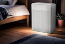 an air purifier next to a bed