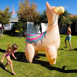 kids playing around a giant inflatable llama sprinkler
