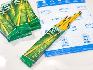 A pack of Ticonderoga pencils spilling out of their box on top of an Amazon mailing envelope on a table next to more boxes of ...