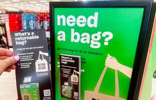 Someone holding up a returnable bag brochure next to a sign in Target
