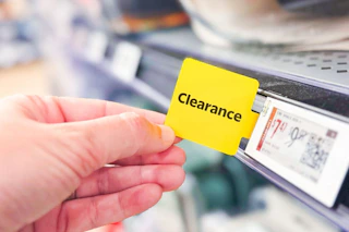 yellow clearance tag with hand holding it straight