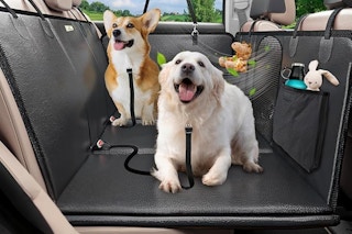 Two dogs sit on a hard bottom car seat that attaches to front and back headrests to provide a larger flat area for dogs in the car.