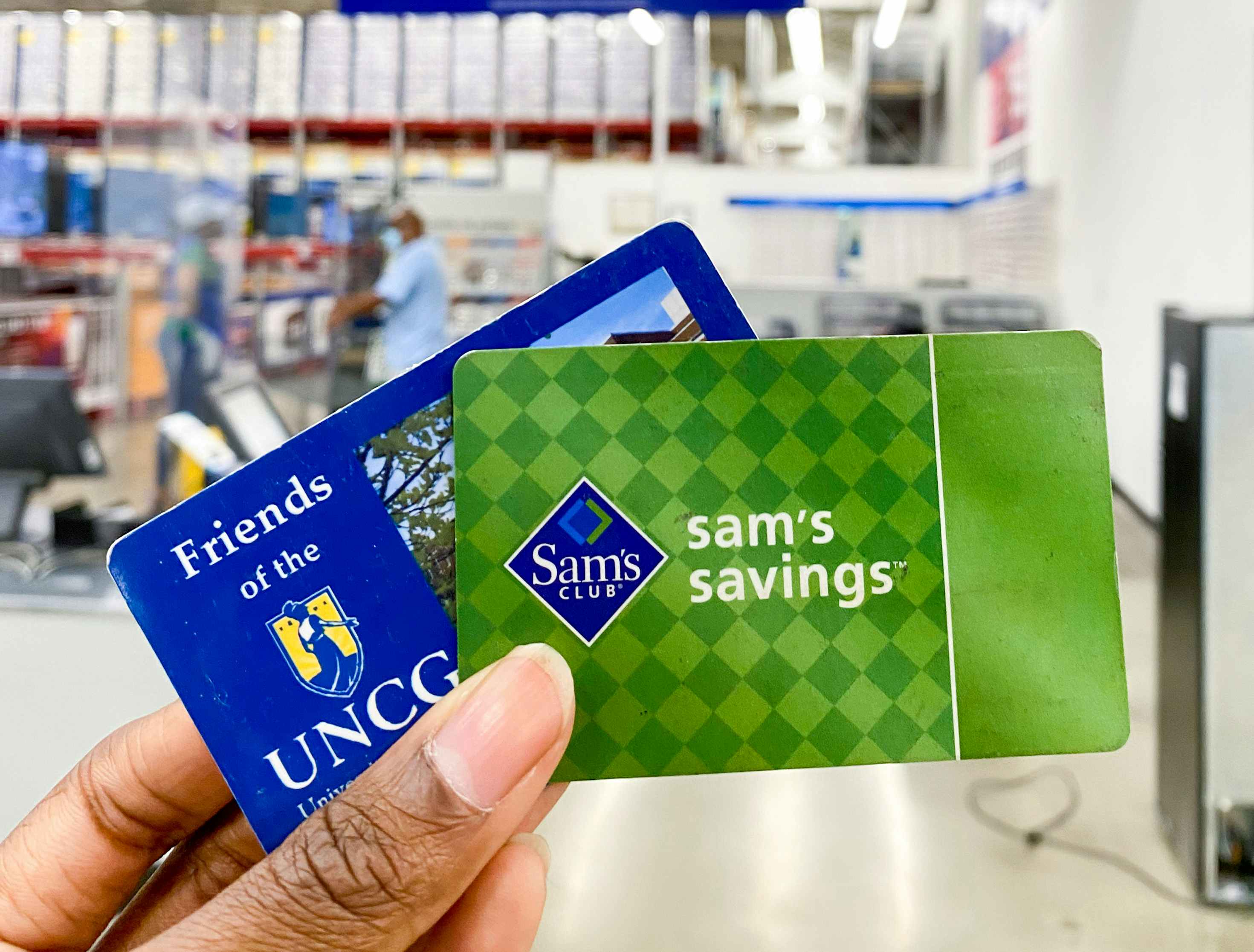 A person holding a student ID and a sams club gift card in front of the members service counter