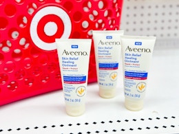 3 aveeno skin relief healing ointments in front of a target basket