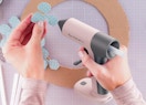 a person using a pink hot glue gun on a paper flower