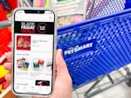 A person holding a cell phone displaying the PetSmart 2022 Black Friday sneak preview page on their website