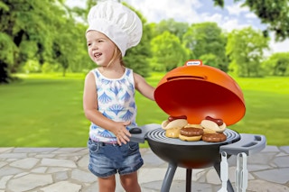 Lifestyle image of small child playing with the Little Tikes grill toy outdoors