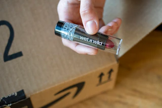 a hand holding a tube of lipstick