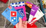 person holding dominos, bath and body works, regal, wayfair, and h&m gift cards over a cart