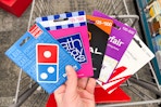 person holding dominos, bath and body works, regal, wayfair, and h&m gift cards over a cart