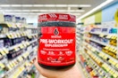 person holding a jar of pre-workout in an aisle