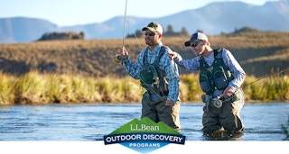 two men wade in stream with waders and fishing poles for ll beans free classes