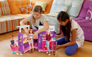 stock photos of two girls playing with barbie food truck in living room