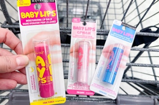 hand holding maybelline baby lips lip balm over a cart with other lip balms