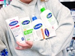 5 Cetaphil products being held by a person in Walmart store