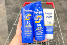 hand holding three coppertone sunscreens over a shopping cart