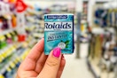 person holding a package of rolaids in an aisle
