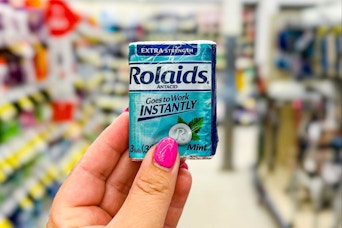 person holding a package of rolaids in an aisle