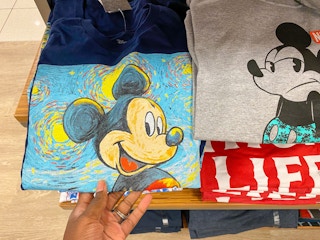 A hand holding a graphic tee with Mickey Mouse on it