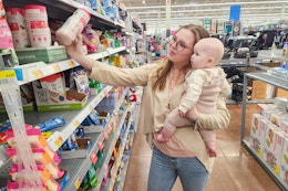 a woman shopping at walmart holding a baby