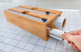 person using foil plastic wrap bamboo storage organizer cutter dispenser