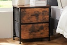 Brown nightstand sitting next to a bed.