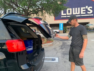man closing trunk in parking lot of lowes