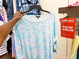 a dress being held In hand next to a clearancee sign reading "last act"