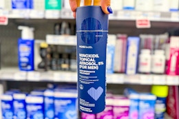 person holding a bottle of men's minoxidil hair growth