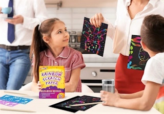 A family with a rainbow scratch paper art set.
